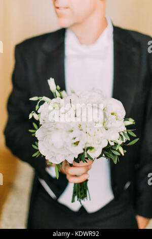Mariage merveilleux bouquet de pivoines blanches dans les mains de l'époux. Banque D'Images