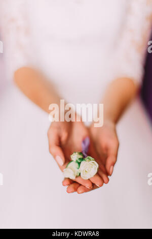 Les mains de la mariée sont maintenant la petite Boutonnière de roses blanches. Banque D'Images