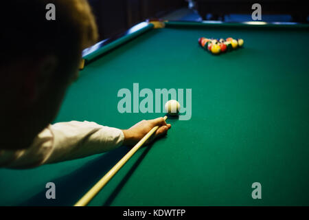 Billard américain. Homme jouant au billard, au snooker. Player s'apprêtait à tourner, frapper la bille blanche. Banque D'Images