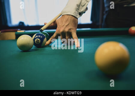 Billard américain. Homme jouant au billard, au snooker. Player s'apprêtait à tourner, frapper la bille blanche. Banque D'Images