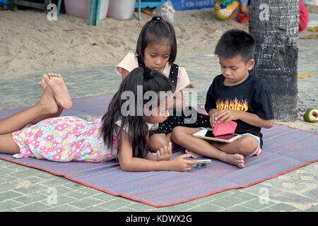 Les enfants jouent dehors avec les smartphones et tablettes iPad Banque D'Images