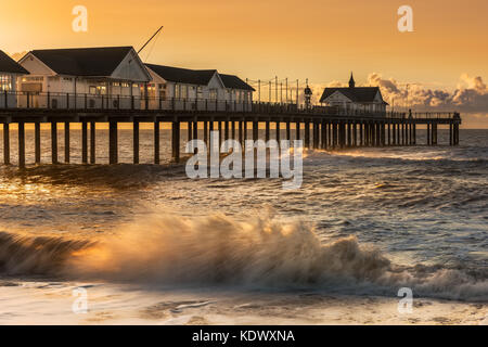 Sur un matin de tempête au début d'août le ciel devient orange comme le soleil se lève derrière la jetée dans la célèbre ville balnéaire de Suffolk Southwold. Banque D'Images