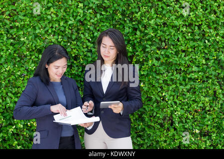 L'équipe de femme d'affaire en prenant sur le travail à l'extérieur du bureau à feuilles vertes,couverture laisser un espace pour l'ajout de texte, concept de leadership féminin Banque D'Images