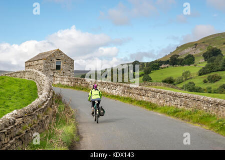 Cycliste sur une route de campagne près de muker dans swaledale, Yorkshire Dales national park, England. Banque D'Images