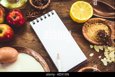 Arrière-plan de cuisson avec du papier pour Noël et d'hiver. notes ingrédients cookies.baking cookies et pâtisserie : pommes, épices, sucre, œufs sur bois Banque D'Images