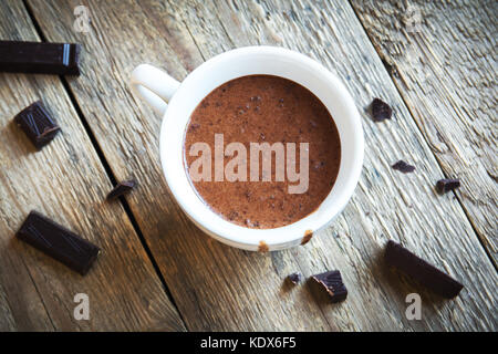 Du chocolat chaud et de morceaux de chocolat sur fond de bois rustique close up. chocolat chaud maison boisson pour l'hiver. Banque D'Images