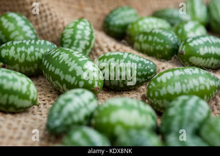 Cucamelon fruits, également connu sous le nom de cornichons aigre mexicain Mexicain, concombres Melothria scabra, ou sur un sac de toile de jute, contexte Banque D'Images