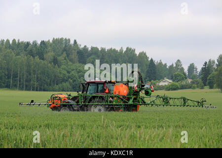 Salo, Finlande - le 25 juin 2016 : agriculteur pulvérise avec champ de blé et de tracteur Valtra amazone 1501 pulvérisateur porté uf en juin dans le sud de la Finlande. Banque D'Images