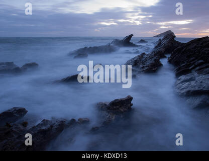 Wembury Beach pointe, Devon, Angleterre. Le fracas des vagues sur les rochers au coucher du soleil. Grande distance de Mewstone. 20 m au large de la côte sud-chemin. Banque D'Images