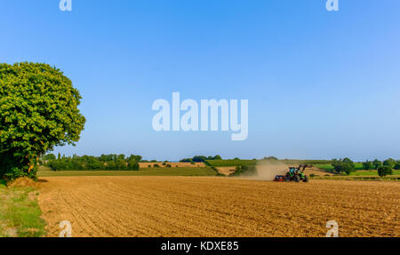 Le hersage du tracteur un champ dans la campagne en été, Orne Normandie France Banque D'Images