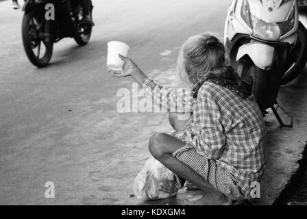 Une vieille femme essayant de faire des extrémités se réunir par la mendicité. Banque D'Images