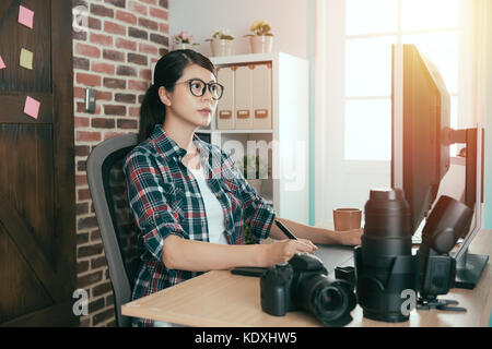 Belle femme photographe professionnelle assis sur un bureau de travail et l'aide de tablette numérique nouvelle édition dessin photo créative dans la mode moderne. Banque D'Images