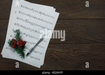 Voir ci-dessus de la musique et joyeux noël concept background.feuille de papier et note festive floue rouge sur sapin en bois brun moderne au bureau à domicile 24 Banque D'Images