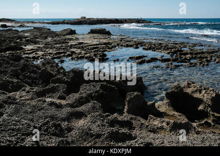 Un pêcheur solitaire se trouve sur le bord d'une formation rocheuse sur la mer méditerranée. Banque D'Images