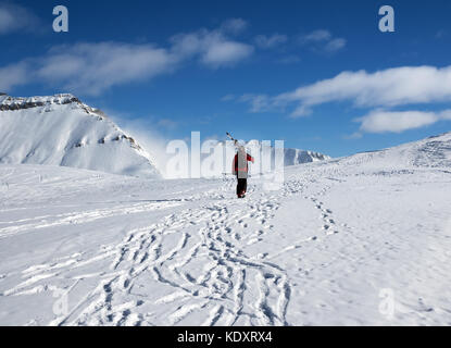 Avec skieur skis sur l'épaule aller jusqu'en haut de la montagne dans jolie journée soleil. Montagnes du Caucase en hiver, la Géorgie, la région Gudauri, Mt. Kudebi. Banque D'Images