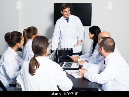 De jeunes spécialistes positive en combinaisons blanches ayant la discussion de travaux de recherche Banque D'Images