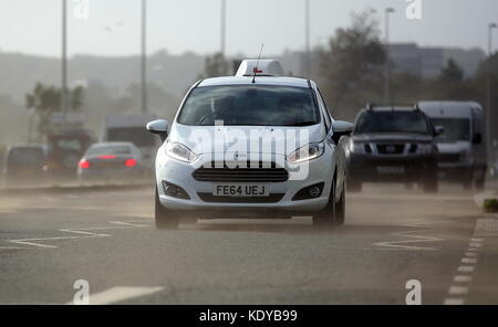 Sur la photo : Voitures voyageant sur la route d'Oystermouth blasted obtenir soufflé par le sable de la plage de Swansea, Royaume-Uni. Lundi 16 octobre 2017 Re : Vestiges de l'ouragan Banque D'Images