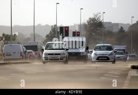 Sur la photo : Voitures voyageant sur la route d'Oystermouth blasted obtenir soufflé par le sable de la plage de Swansea, Royaume-Uni. Lundi 16 octobre 2017 Re : Vestiges de l'ouragan Banque D'Images