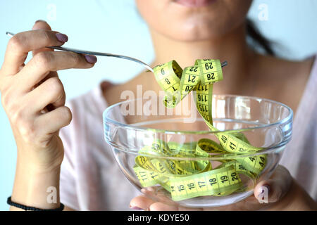 Jeune femme sur l'alimentation manger une mesure jaune bande d'un bol transparent, image abstraite Banque D'Images