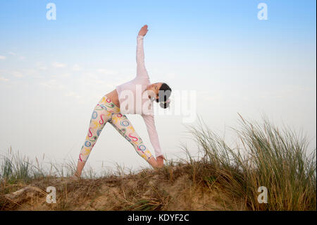 Woman wearing sportswear pratique le yoga dans les dunes de sable Banque D'Images