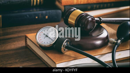 Marteau et un droit de jauge de pression artérielle sur un bureau en bois, fond sombre Banque D'Images