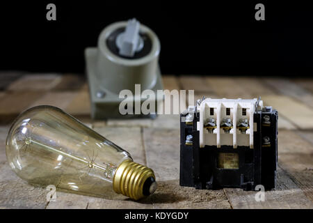 Ancienne Fiche et prise de tension élevée. vieux accessoires électriques. table en bois, fond noir Banque D'Images