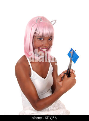 Une belle jeune femme aux cheveux roses et oreilles de lapin de couper sa carte de crédit, souriant et heureux, est isolée pour fond blanc Banque D'Images