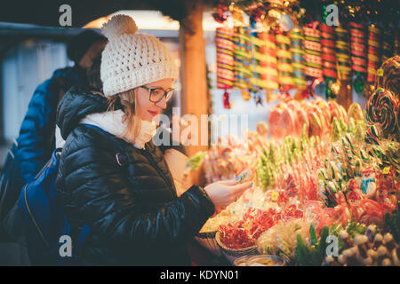 Heureux belle femme sélection traditionnelles fêtes de bonbons sur marché de Noël, l'image aux couleurs Banque D'Images