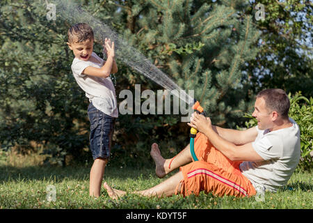 Heureux père et fils jouer dans le jardin à la journée. Les gens s'amusant oudoors. concept de famille heureuse. Banque D'Images