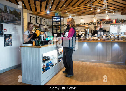 Un client heureux à la caisse avec un membre du personnel souriant comme elle paie pour sa commande de nourriture à la mountain cafe, Aviemore, Scotland, UK Banque D'Images