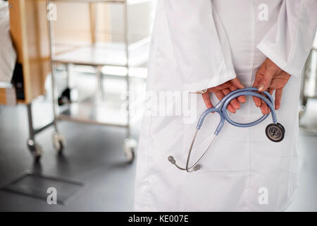 Female doctor holding stethescope. Tourné à l'arrière, pas de tête en photo. Bon, salle de l'Hôpital clinique de style de l'entreprise Banque D'Images