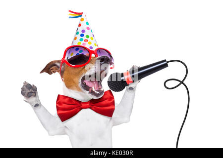 Chien Jack Russell comme une surprise, le chant chanson d'anniversaire comme Karaoké avec micro portant cravate rouge et party hat , isolé sur fond blanc Banque D'Images