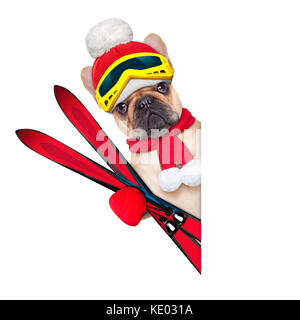 Chien bouledogue français fauve avec équipement de ski, portant ces lunettes , gants , un chapeau et une écharpe rouge,blanc à côté d'une une ouverture vierge ou une affiche, isolé sur blanc Banque D'Images
