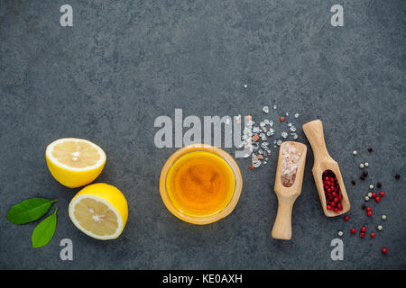 La vinaigrette citron citron ingrédients, l'huile d'olive, sel et poivre de l'himalaya le maïs en pierre sombre arrière-plan avec télévision lay et copiez l'espace. Banque D'Images