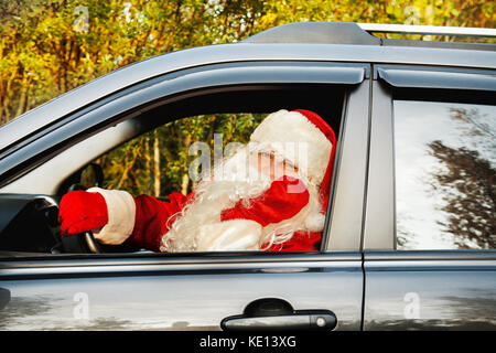 Père Noël authentique. Le père noël conduit une voiture à travers la forêt d'automne. en attente de noël. Banque D'Images