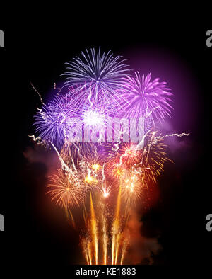 Un grand spectacle de feux d'artifice lumineux avec des roquettes orange dorées et violettes. Banque D'Images