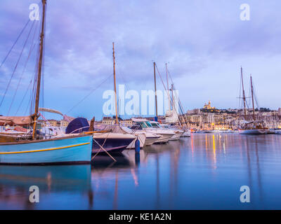 Yachts se reflétant dans les vieux vieux port de Marseille sous notre dame de Paris, France, par nuit. Banque D'Images