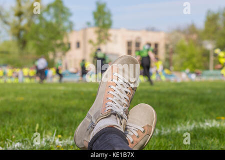 Close up of female regarder match de football : chaussures sur fond de snickers match de football américain Banque D'Images