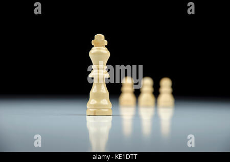 Close-up view of white chess king avec pions blancs sur l'arrière-plan sur fond blanc avec la réflexion Banque D'Images