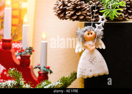 Ange de Noël poupée de chiffon accroché sur couronne de Noël avec des pommes de pins. au milieu d'un bougeoir de fête avec des bougies. Célébration du Nouvel An et de noël Banque D'Images