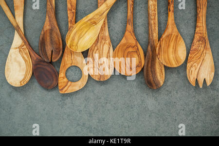 Divers ustensiles de cuisine en bois frontière. cuillères en bois et spatule en bois sombre sur fond de pierre avec une télévision lay et copie espace. Banque D'Images