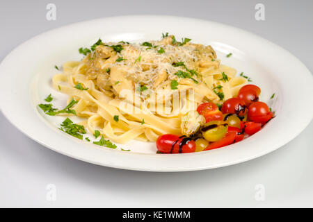 Fresh Handmade Tagliatelles aux champignons des bois, le persil et la salade de tomates cerises sur fond blanc Banque D'Images