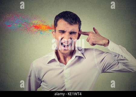 Portrait Portrait jeune homme se suicide avec des armes à feu doigt geste, explosion de couleurs isolé sur fond de mur gris. Les émotions humaines face à expr Banque D'Images