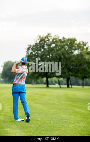 Jeune homme jouant au golf sur une journée ensoleillée sur un magnifique parcours de golf Banque D'Images