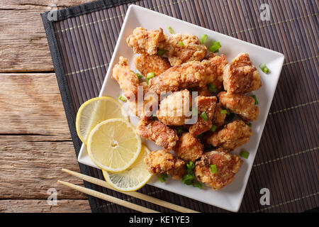 Partie fried chicken karaage avec le citron et l'oignon sur une assiette sur la table. haut horizontale Vue de dessus Banque D'Images