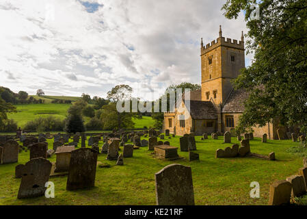 L'église Saint Eadburgha en pierre des cotswolds et son ancienne cour avec ses collines ondulantes des Cotswolds en arrière-plan. Banque D'Images