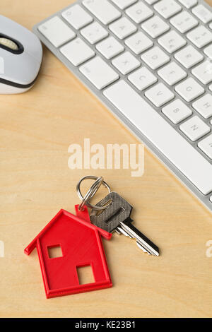 Chambre rouge chambre porte clé avec chaîne et pendentif clé clavier de l'ordinateur sur un bureau en bois - Location de maison ou d'acheter en ligne concept Banque D'Images