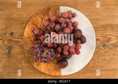 Les raisins et les prunes rouges sur fond de bois et de marbre Banque D'Images