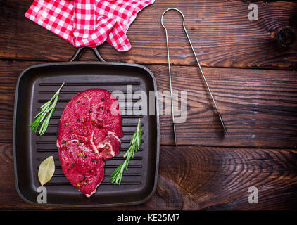 Steak de boeuf cru sur un quart noir pan, l'espace vide sur la droite Banque D'Images