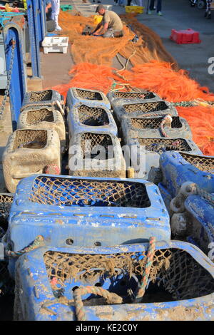 Whitstable, uk - 15 octobre 2017 : les boîtes de pêche colorés et des filets de pêche avec un pêcheur travaillant sur ses filets dans l'arrière-plan Banque D'Images